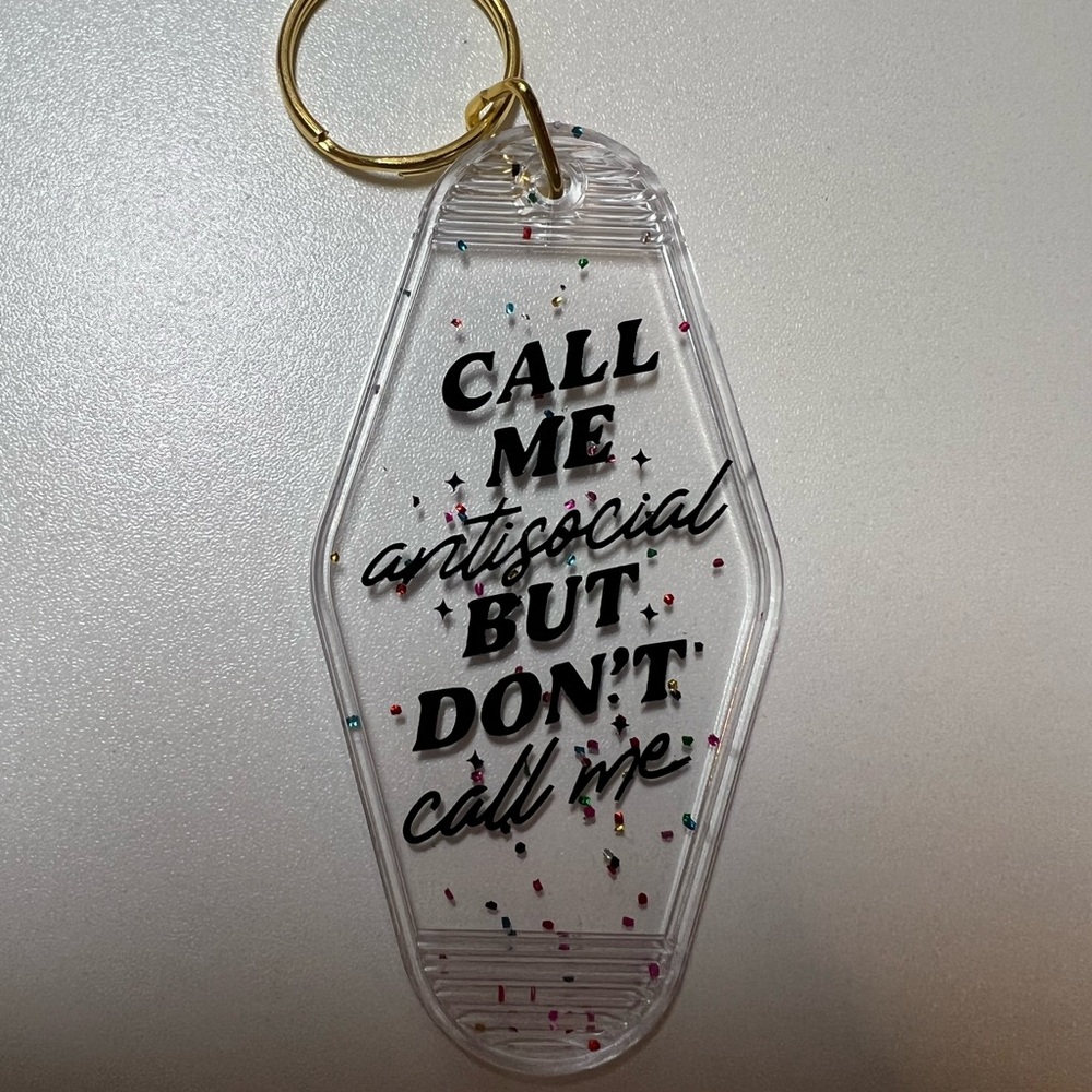 “Call Me Antisocial But Don’t Call Me” keychain with confetti/sparkle background